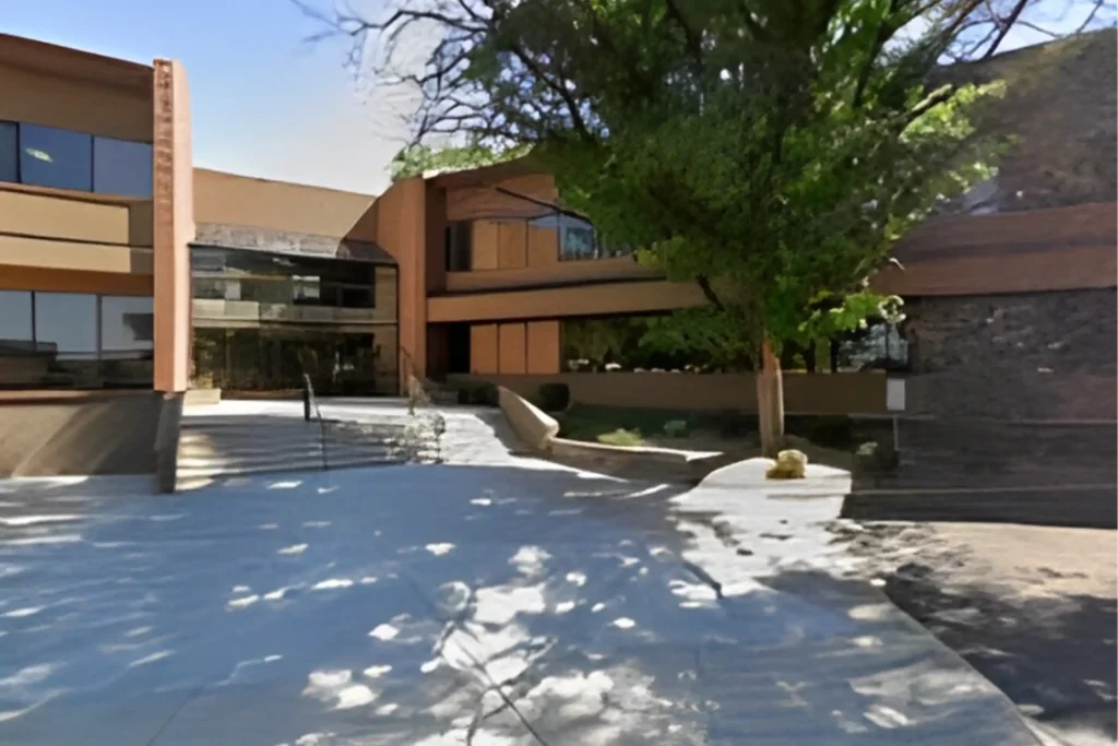 Exterior of a modern office building with a concrete courtyard and large windows.