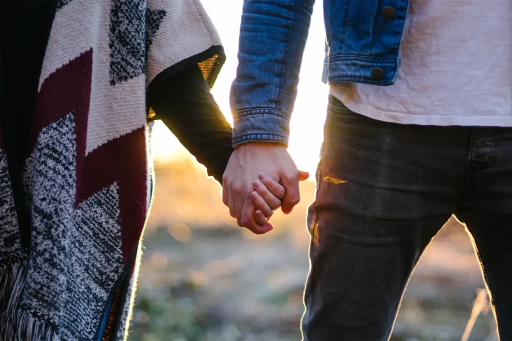A supportive photo of a couple holding hands during a golden sunset, symbolizing rebuilding connection.