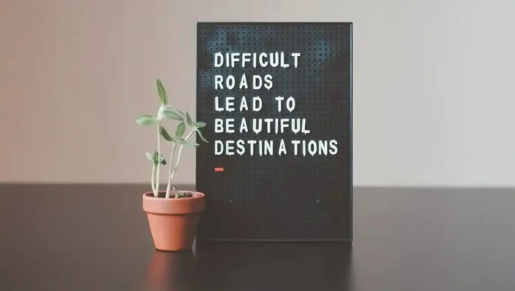 An encouraging photo of a letter board with the quote 'Difficult roads lead to beautiful destinations' and a small growing plant, symbolizing the hopeful journey of recovery.