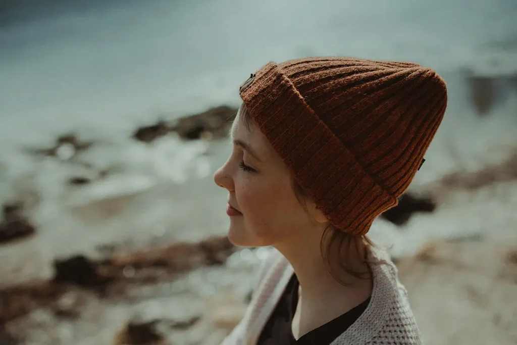 A serene photo of a woman in a beanie with her eyes closed, looking calm and reflective how EMDR helps the brain heal from trauma.