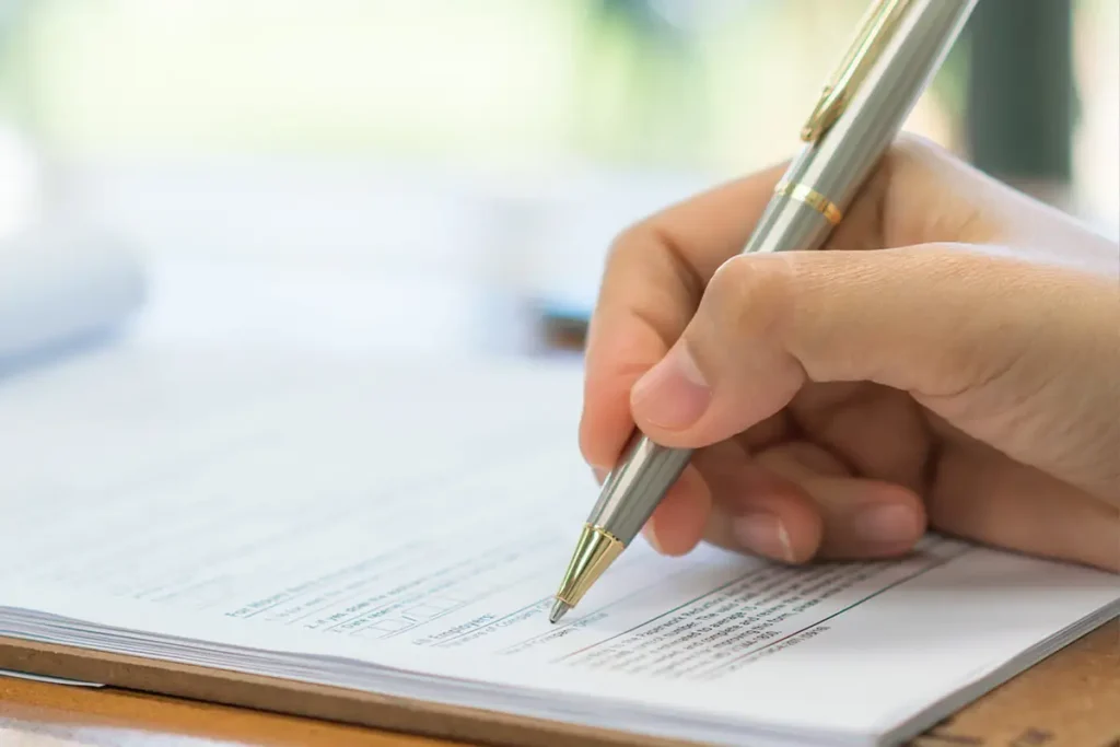 Fee policies for Medicaid recipients, illustrated with a close-up photo of a person filling out a form with a pen.