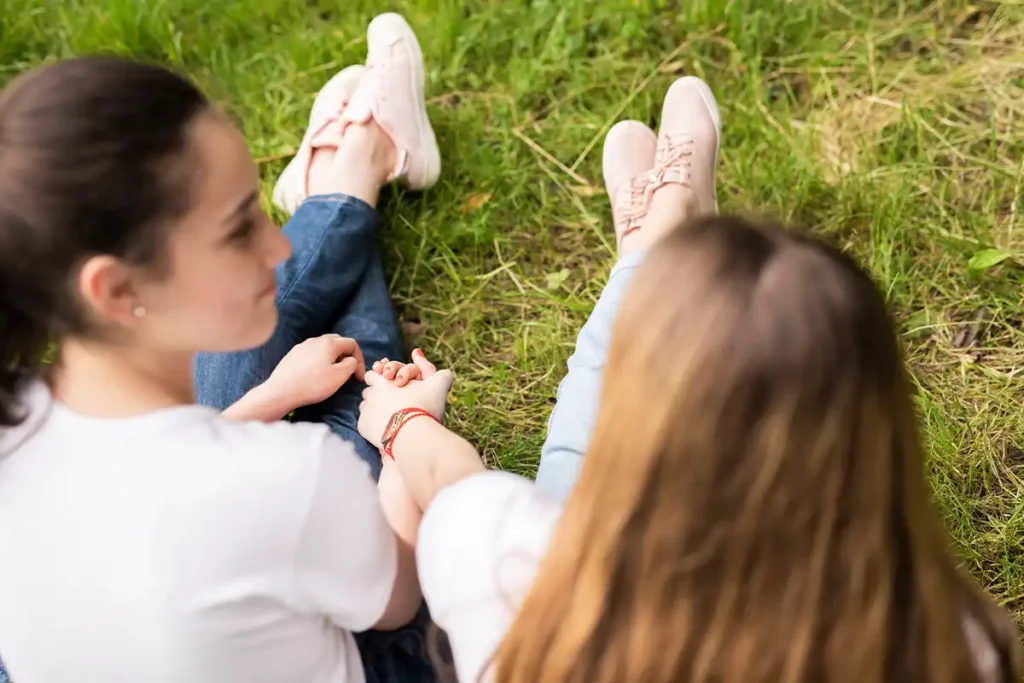 Two teenage girls holding hands about key challenges that therapy can address for children and teens.