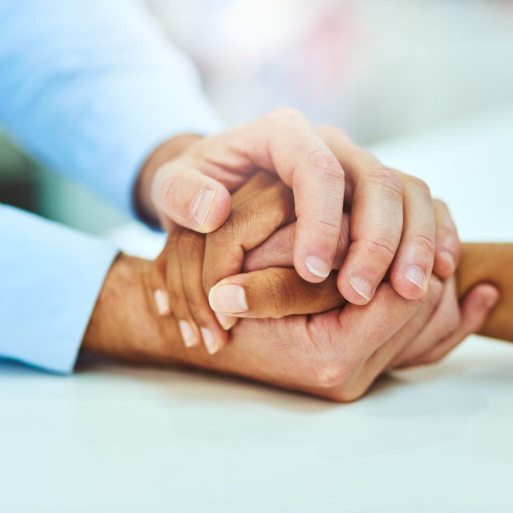 Hands supporting other hands in a warm comforting hold that comes from compassionate therapy