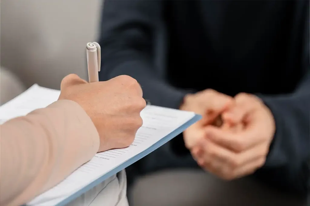 Signs of readiness for Ketamine Integration Therapy, illustrated with a photo of a therapist writing on a clipboard during a session.