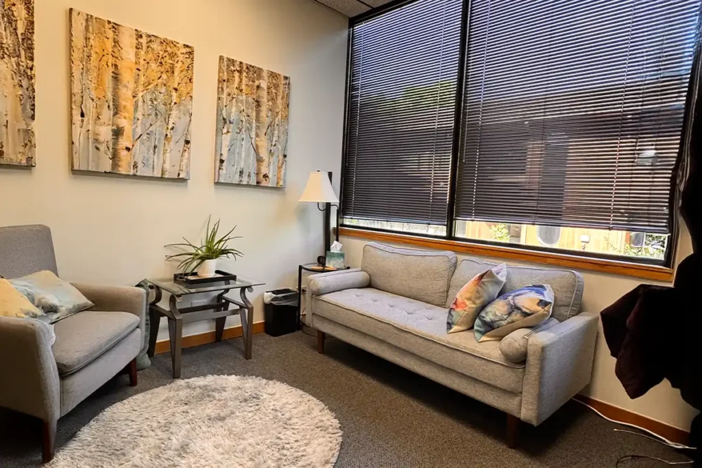 A welcoming therapy office with a couch and armchair, illustrating the benefits of child and teen therapy using methods like CBT and EMDR.