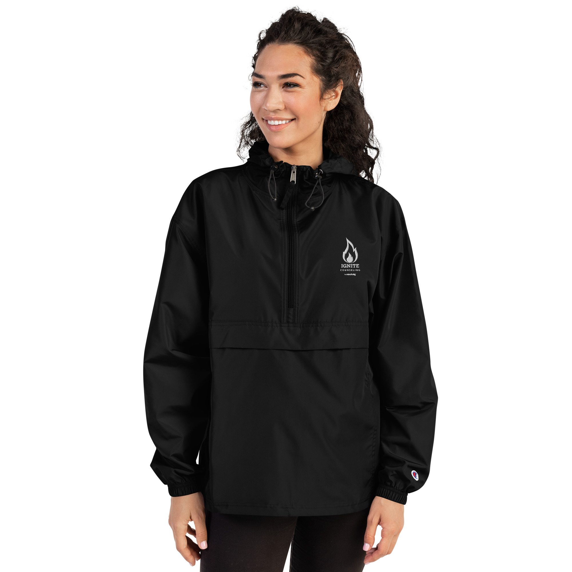 Smiling woman modeling a black windbreaker jacket featuring the Ignite Counseling logo.