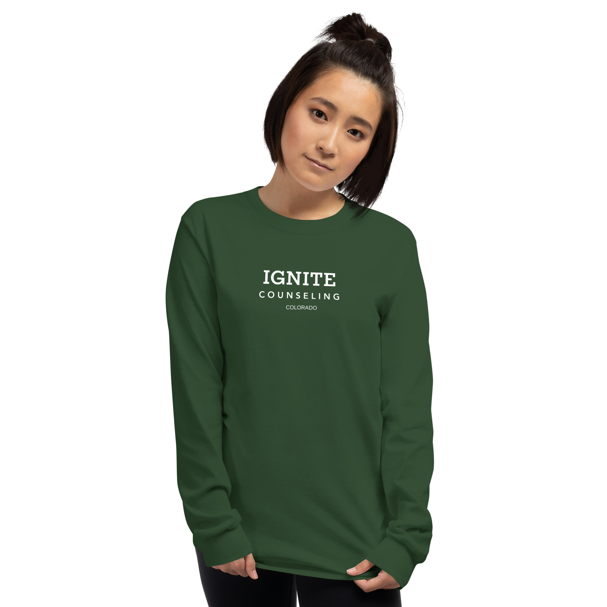 Woman modeling a forest green long-sleeve t-shirt featuring the Ignite Counseling Colorado logo.