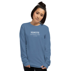 Woman modeling a steel blue long-sleeve t-shirt featuring the Ignite Counseling Colorado logo.