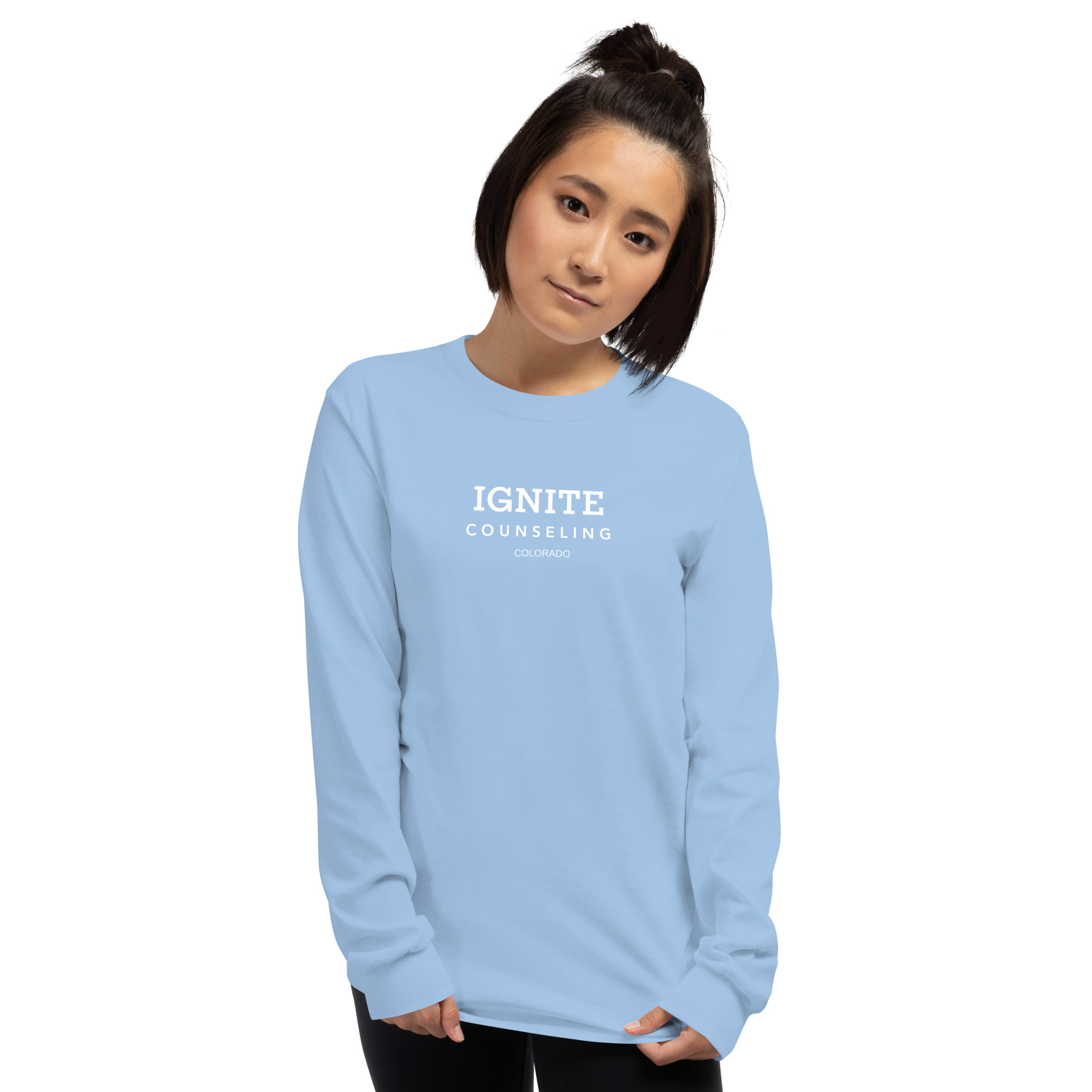 Woman modeling a light blue long-sleeve t-shirt featuring the Ignite Counseling Colorado logo.