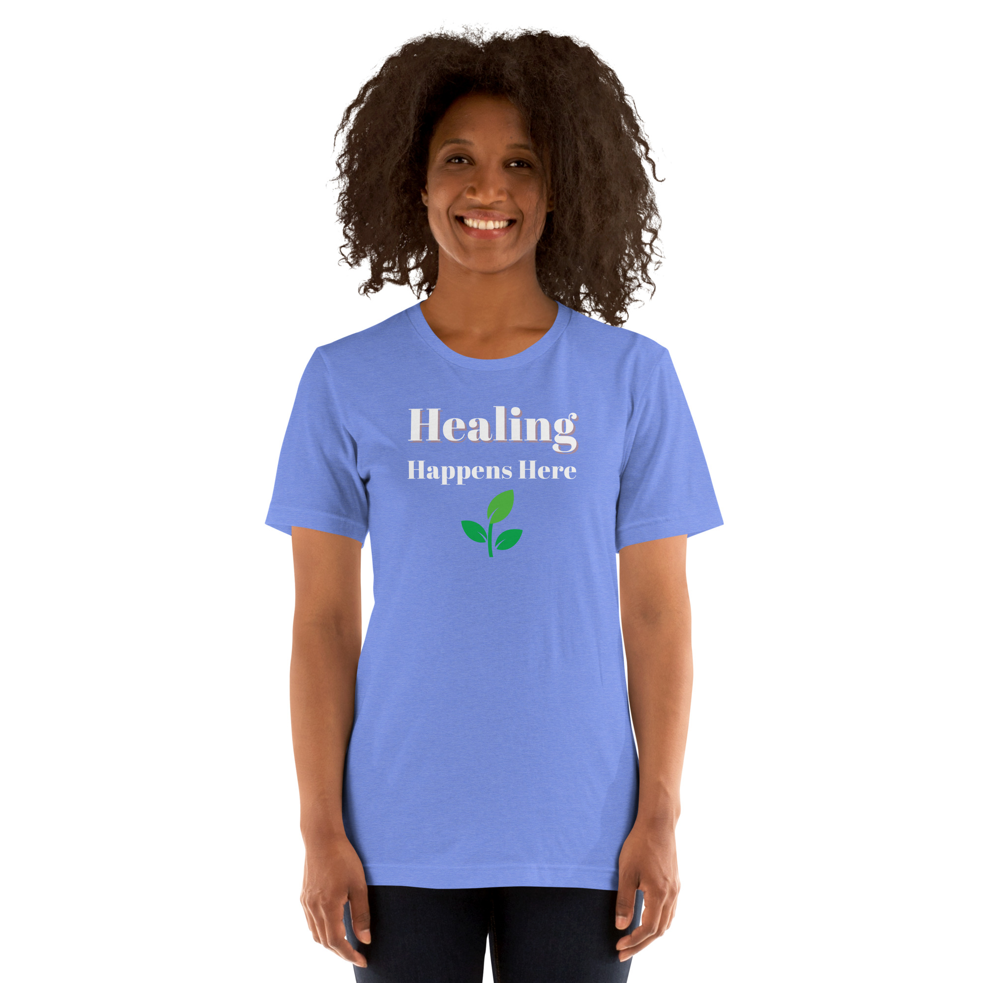 Smiling woman modeling a periwinkle blue t-shirt featuring the text 'Healing Happens Here' and a green leaf graphic.
