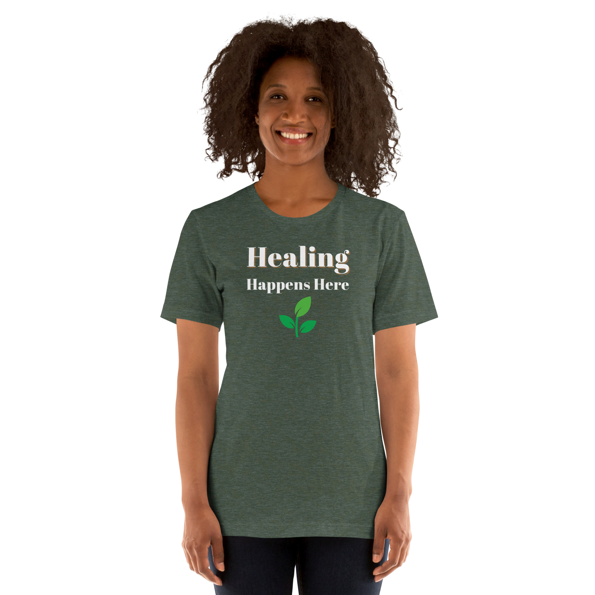 Smiling woman modeling a heather military green t-shirt featuring the text 'Healing Happens Here' and a green leaf graphic.