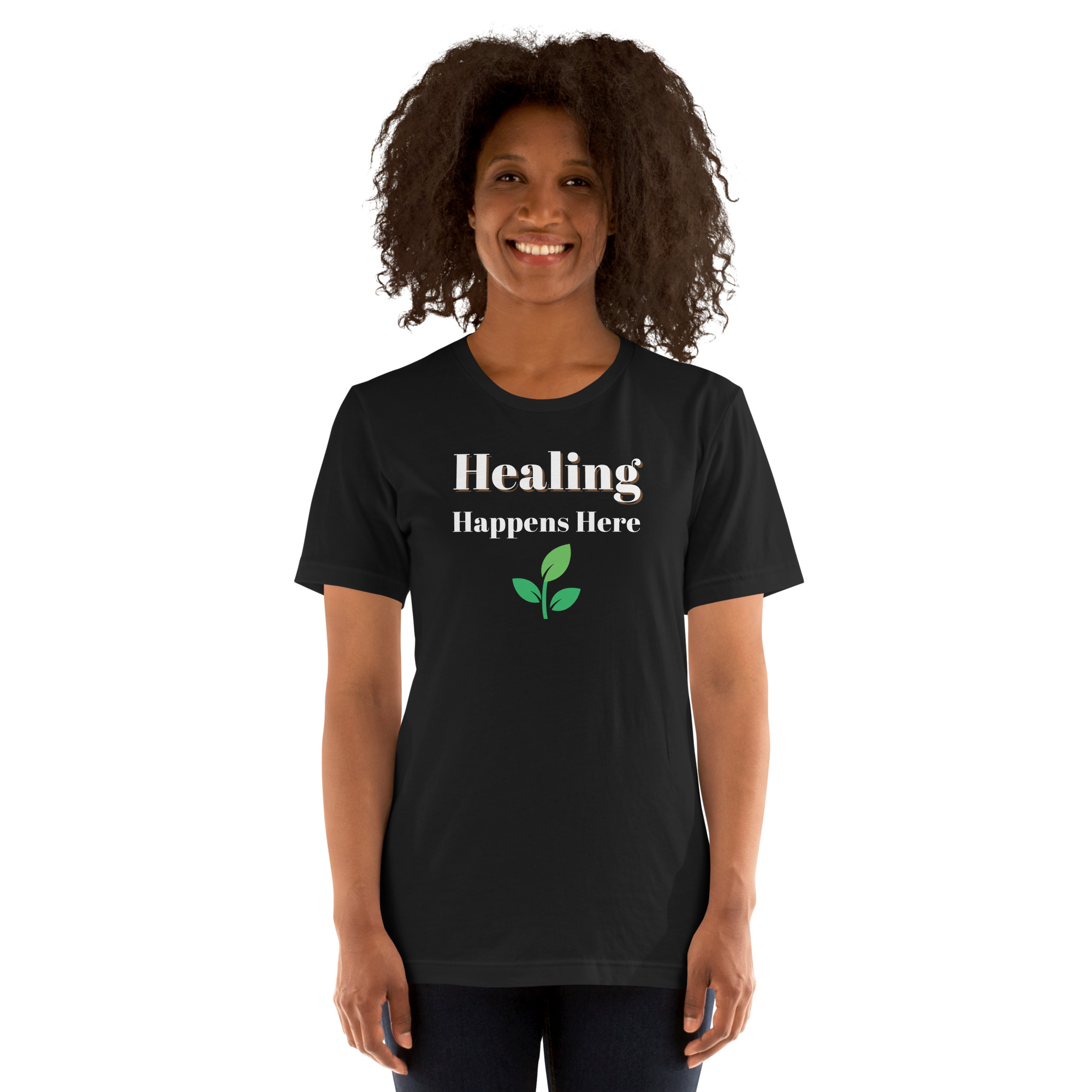 Smiling woman modeling a black t-shirt featuring the text 'Healing Happens Here' and a green leaf graphic.