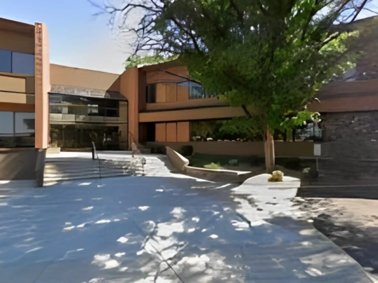 Exterior of a modern office building with a concrete courtyard and large windows.